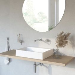 Drewniany blat w łazience z prostokątną umywalką nablatową i syfonem w kolorze stali deante